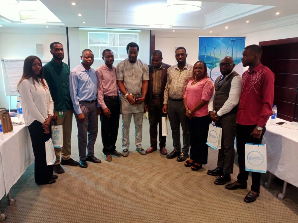 A group of eleven people stands indoors in front of a presentation screen and posters, posing for a photo during an NG Content Partner Spotlight event or workshop.