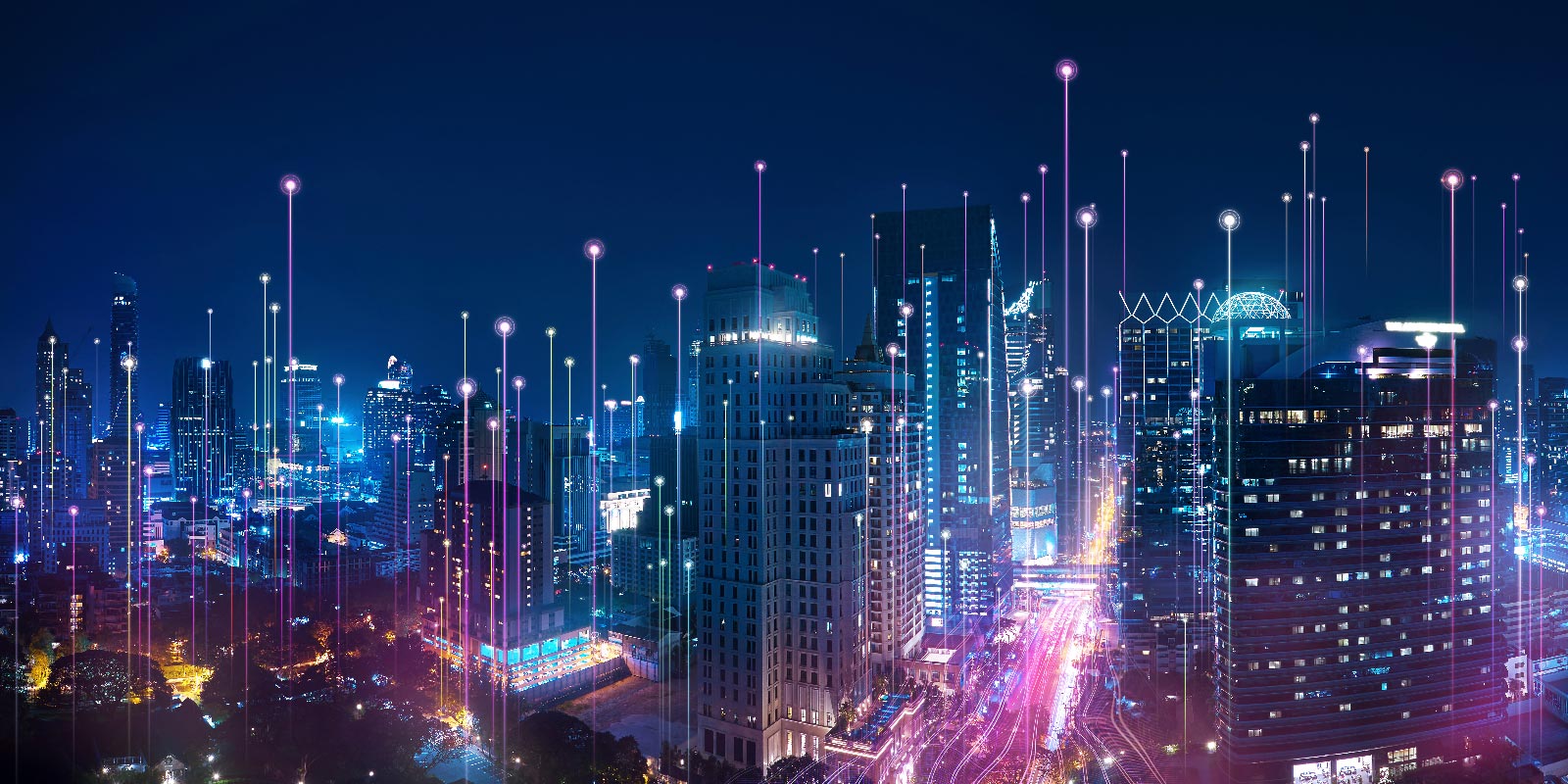 Eine Luftaufnahme einer Stadt bei Nacht mit blauen und violetten Linien, die in die Luft ragen und die digitalen Verbindung symbolisieren