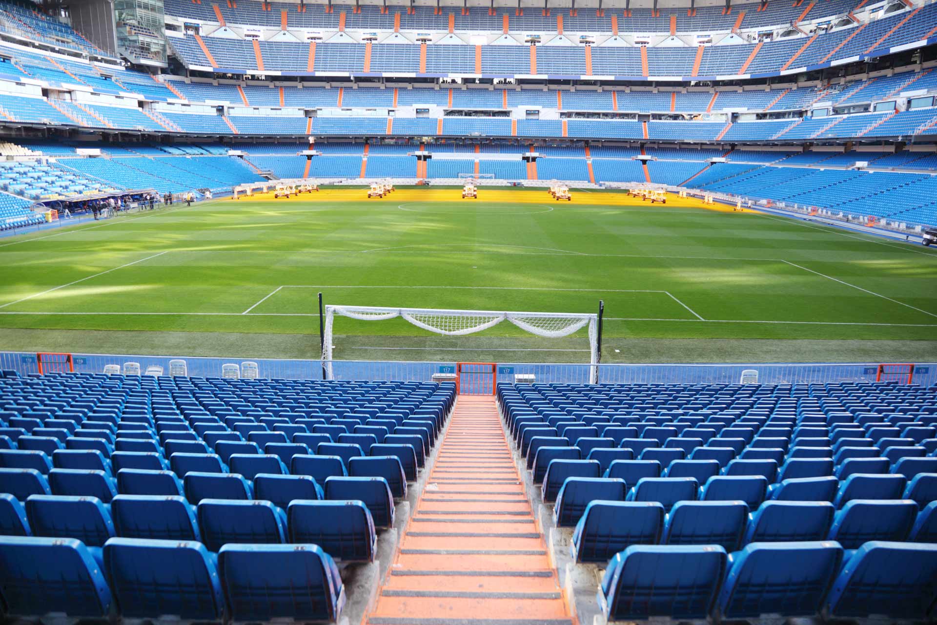 The inside of a stadium, showcasing blue seats and a soccer field during a game.