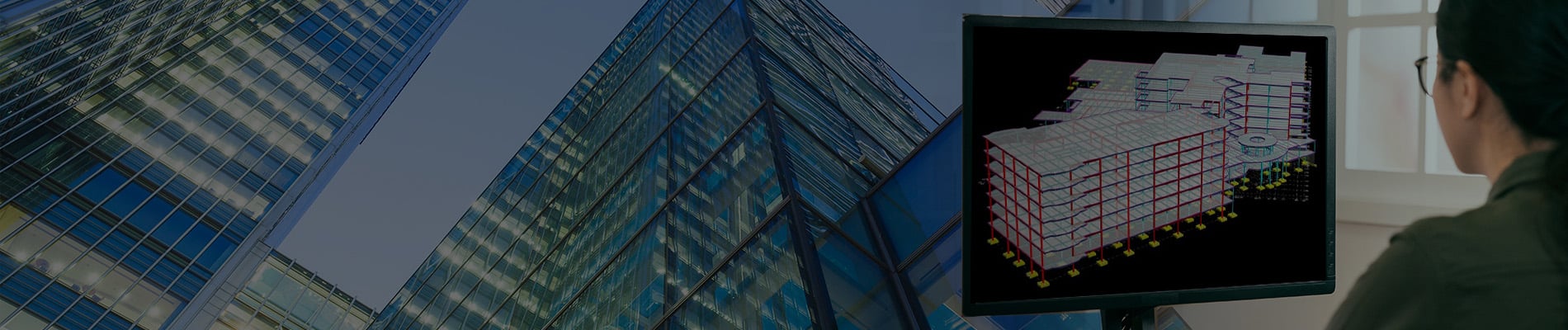 Architect reviewing a 3D building model on a computer screen with modern glass office buildings in the background, utilizing Structural WorkSuite for enhanced structural analysis.