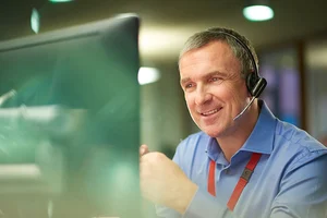 Smiling man with headset sitting in front of a computer monitor, planning resilient rail infrastructure.