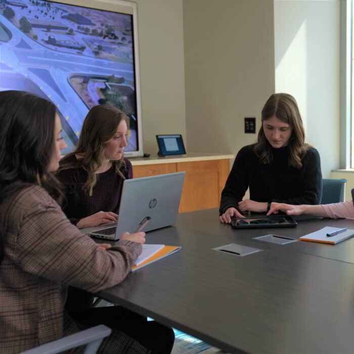 Grupo de mujeres alrededor de un escritorio conversando sobre un proyecto