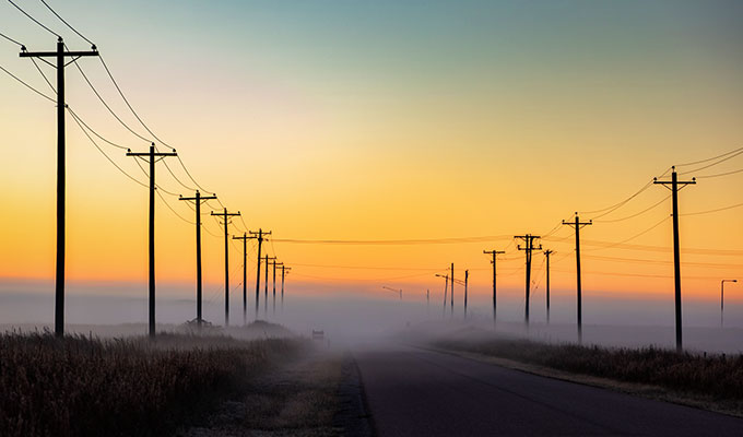 A foggy road with power lines in an industrial area.