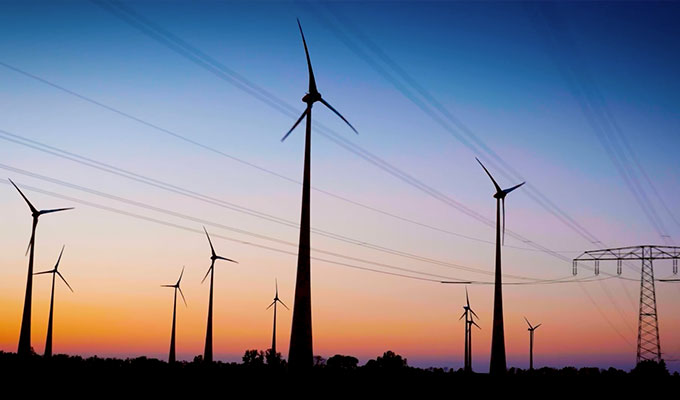 imagem de moinhos de vento e linhas de energia ao anoitecer para produção de energia