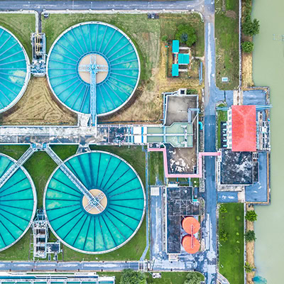 Aerial view of a water treatment facility showing large circular settling tanks, rectangular buildings, and surrounding grounds.