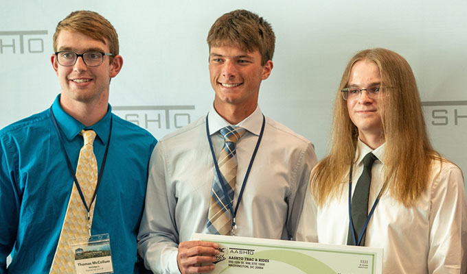 Bentley Systems sponsert auf der Frühjahrstagung der AASHTO einen Brückenwettbewerb für Studierende. 3 Studierende halten einen großen Scheck in der Hand und lächeln.