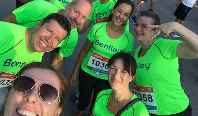 grupo de compañeros de trabajo con camisas de Bentley de color verde brillante preparándose para una carrera en grupo