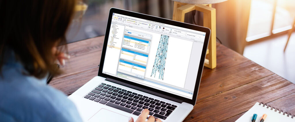 A person using a laptop with architectural design software on the screen, showcasing digital tower design and structural details.