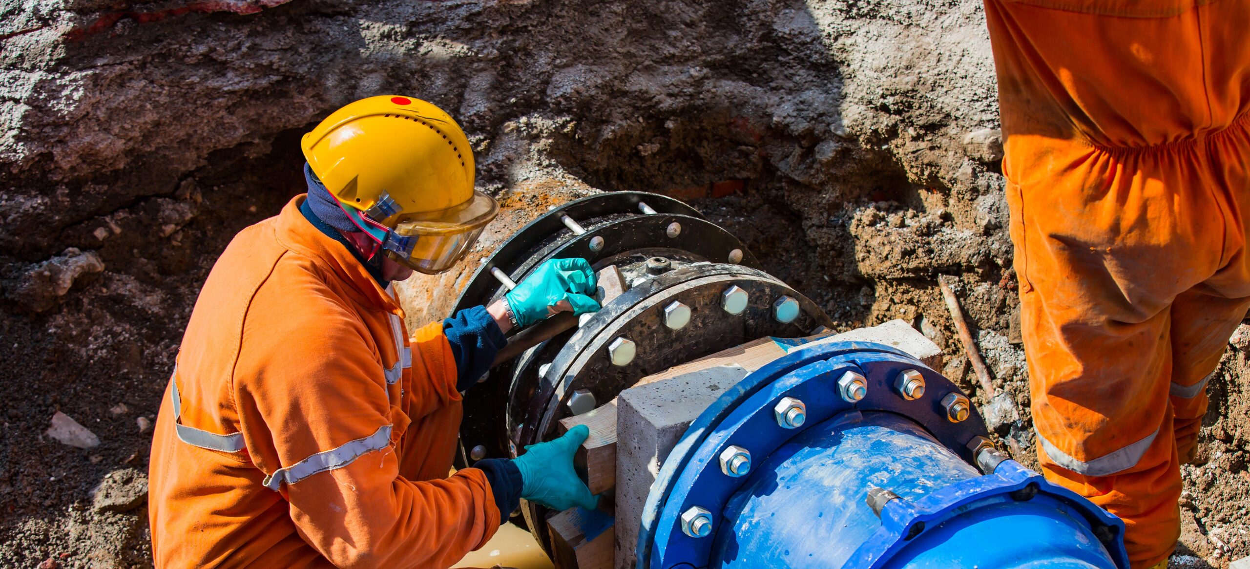 Two construction workers unlocking hidden savings while working on a water utilities pipe.