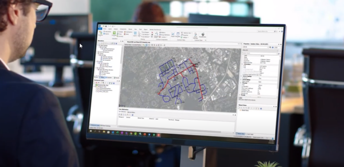 A man is using the WaterGEMS software to analyze a map on a computer screen.