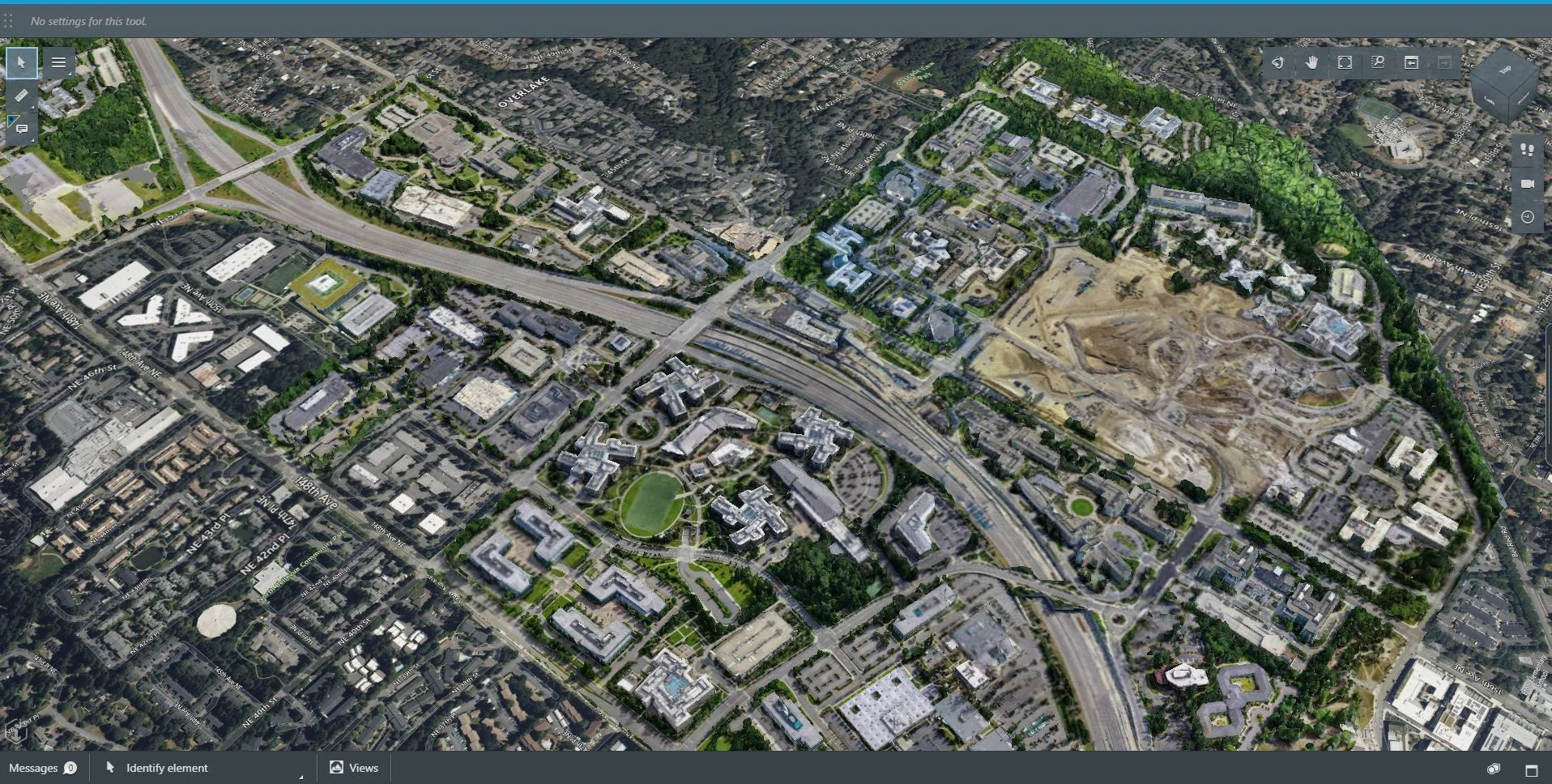 Aerial view of a developed area with multiple roads intersecting, surrounded by buildings and green spaces, featuring reality capture technology for active construction to one side.