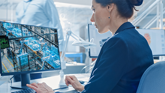 A woman is demoing a computer in a factory.