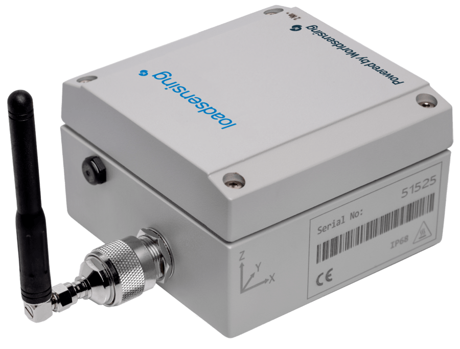 A gray electronic device labeled “load sensing” with an attached black antenna, serial number, and certification symbols on one side.